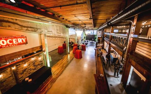 Aerial view of the main floor from the mezzanine, styled for a cocktail event beside the vintage 'Brownie Grocery' sign