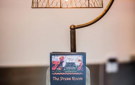 A brass reading lamp beside The Press Room's own card